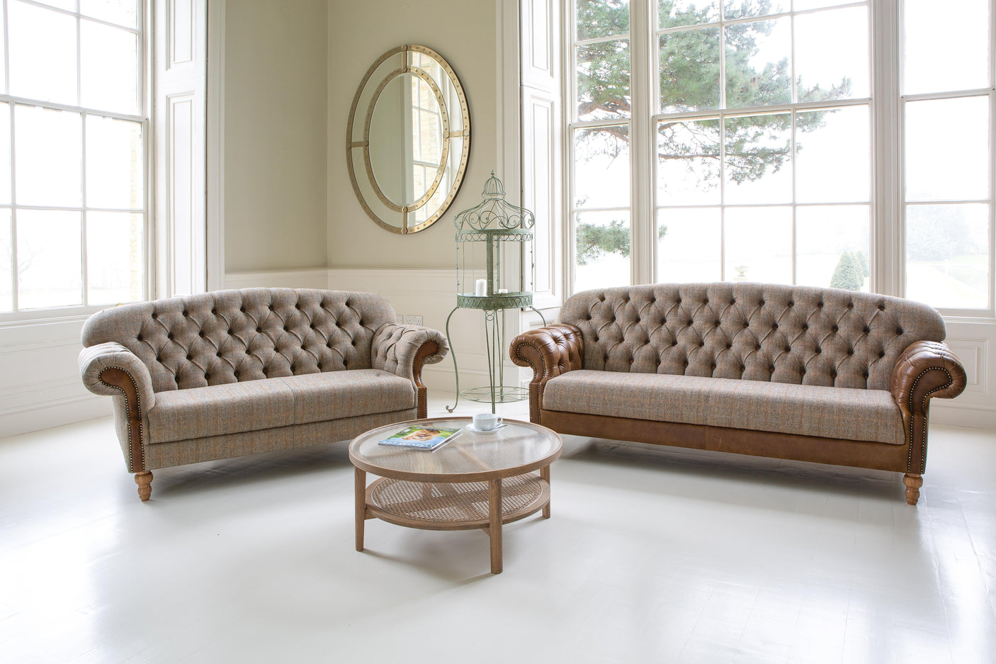 Button-tufted fabric sofas with leather arms and round wooden coffee table in bright living room