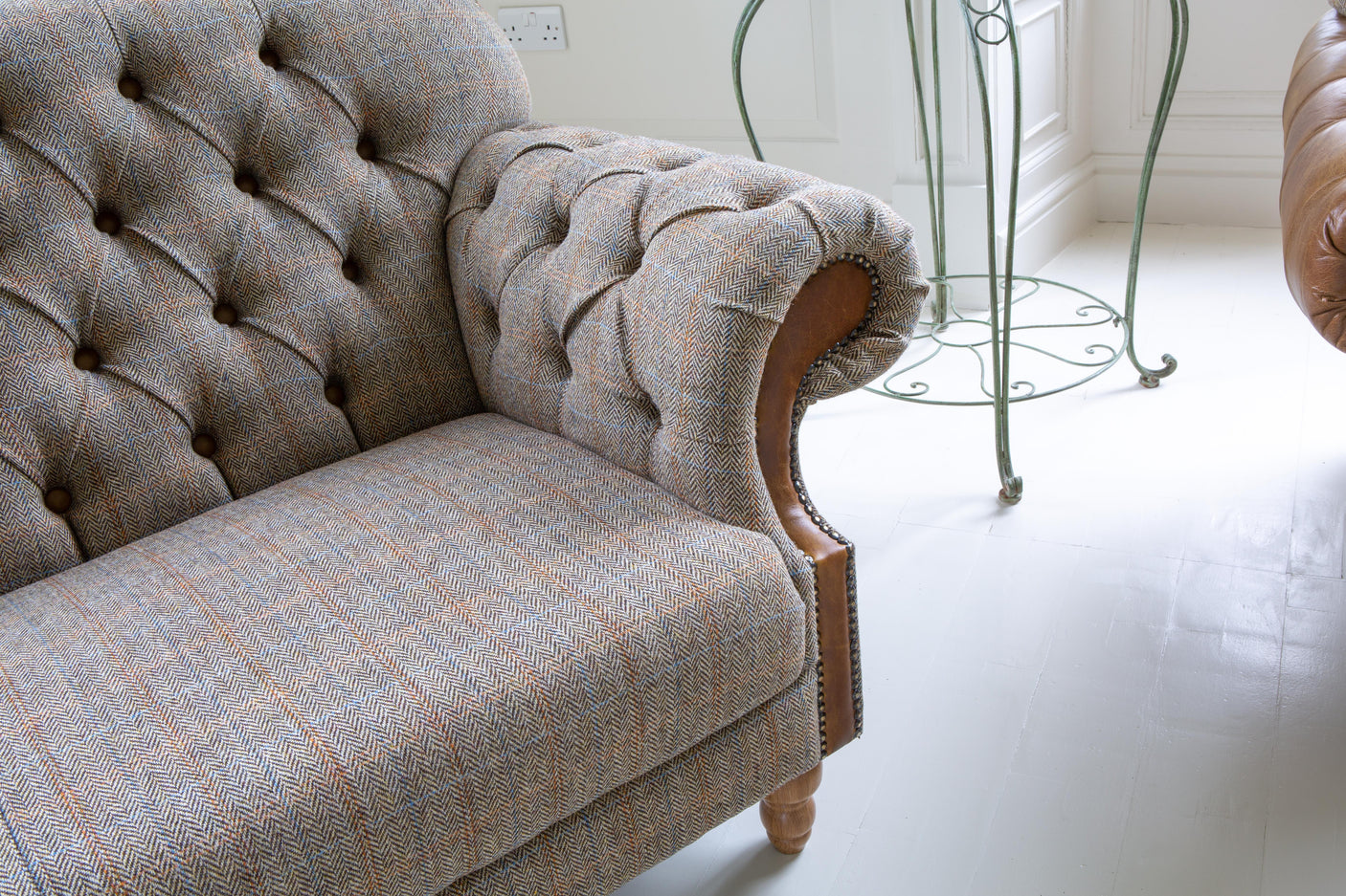 Herringbone fabric sofa with button-tufted backrest and wooden legs in bright living room