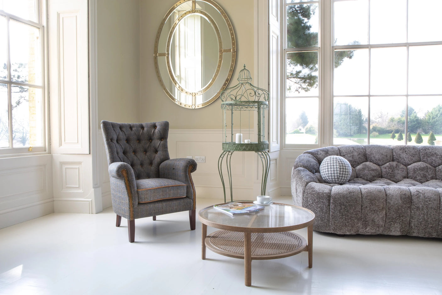 Modern grey fabric sofa with circular coffee table in bright living room with large windows
