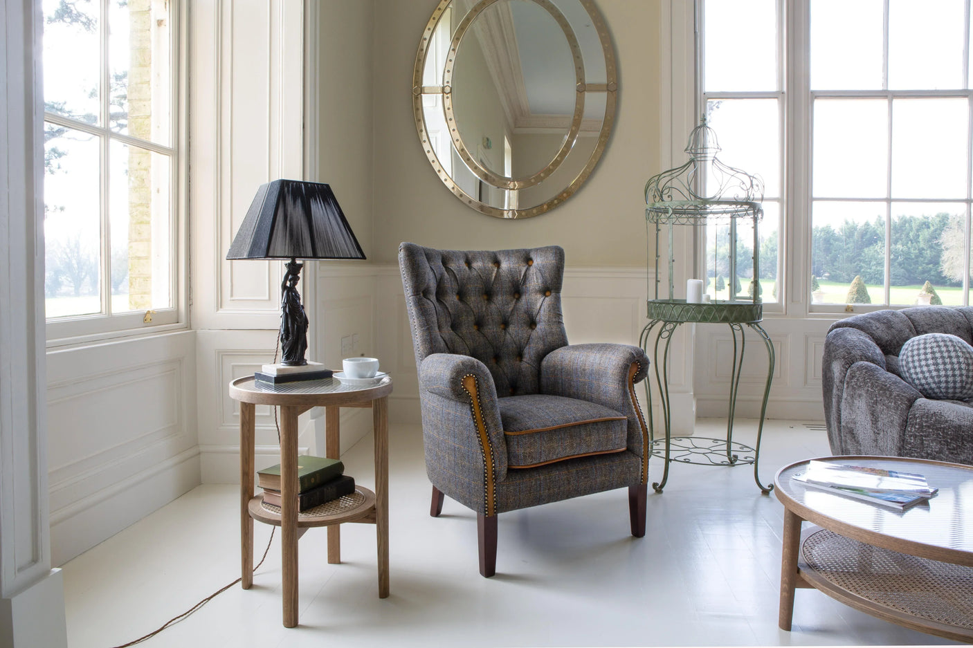 Grey fabric armchair with button back and stud detail in bright living room