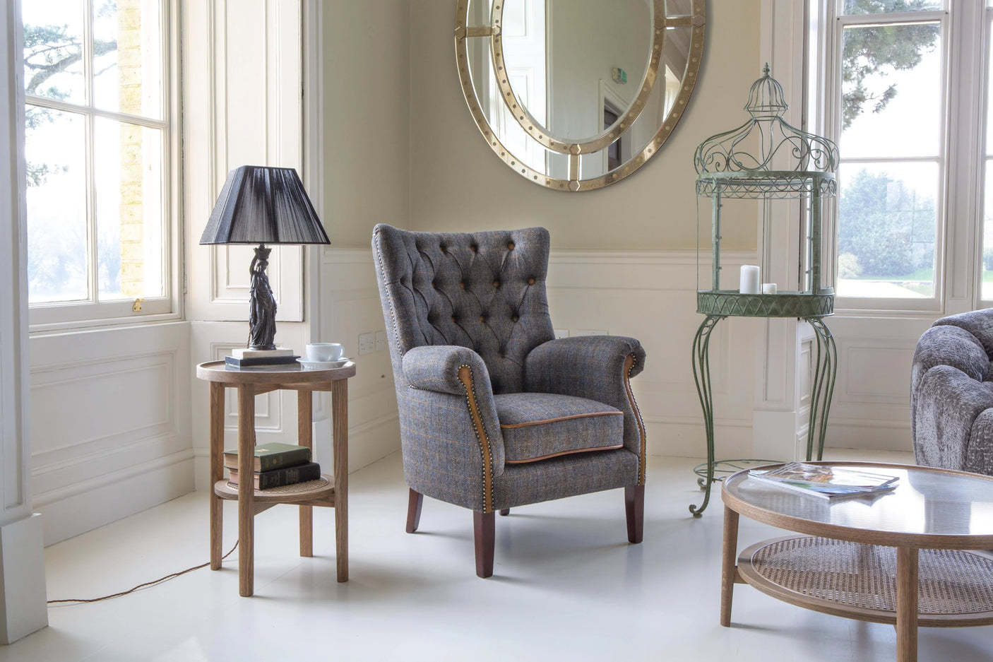 Grey upholstered armchair with button tufting in bright living room corner