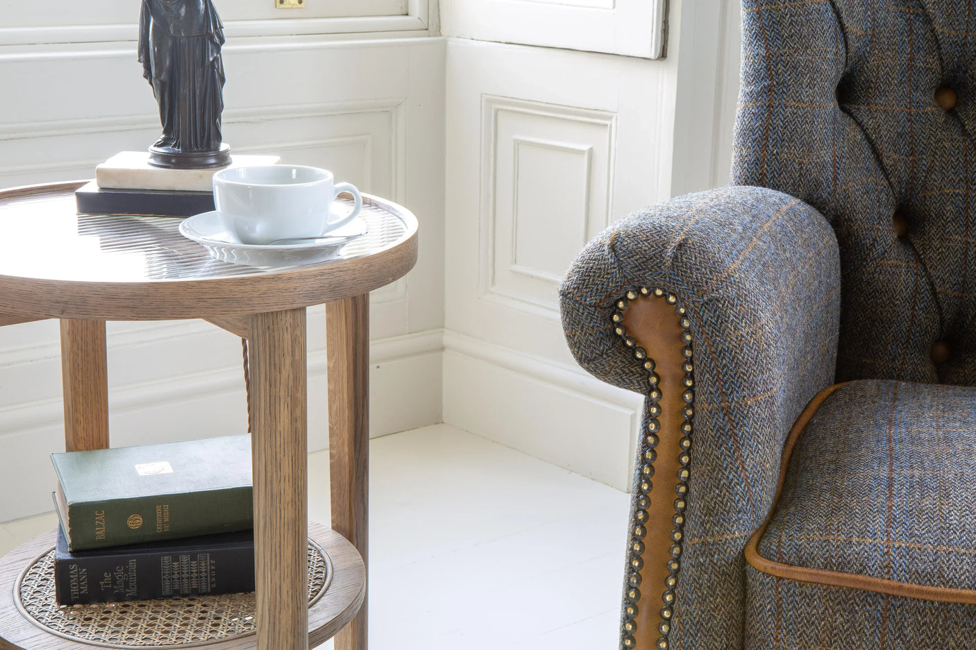 Upholstered armchair with tweed fabric and wooden side table with cup and books