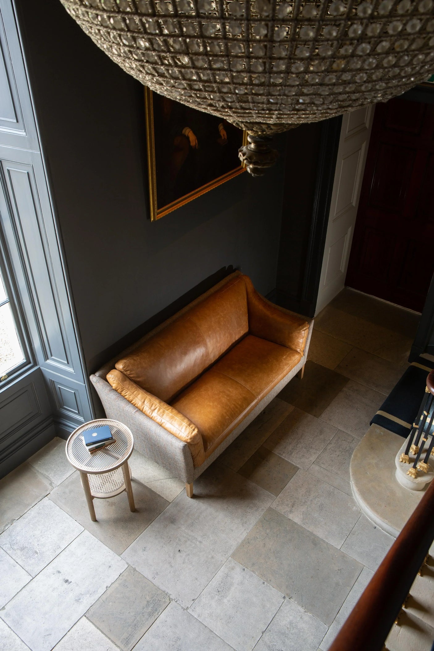 Tan leather sofa with fabric sides in hallway beside small round side table