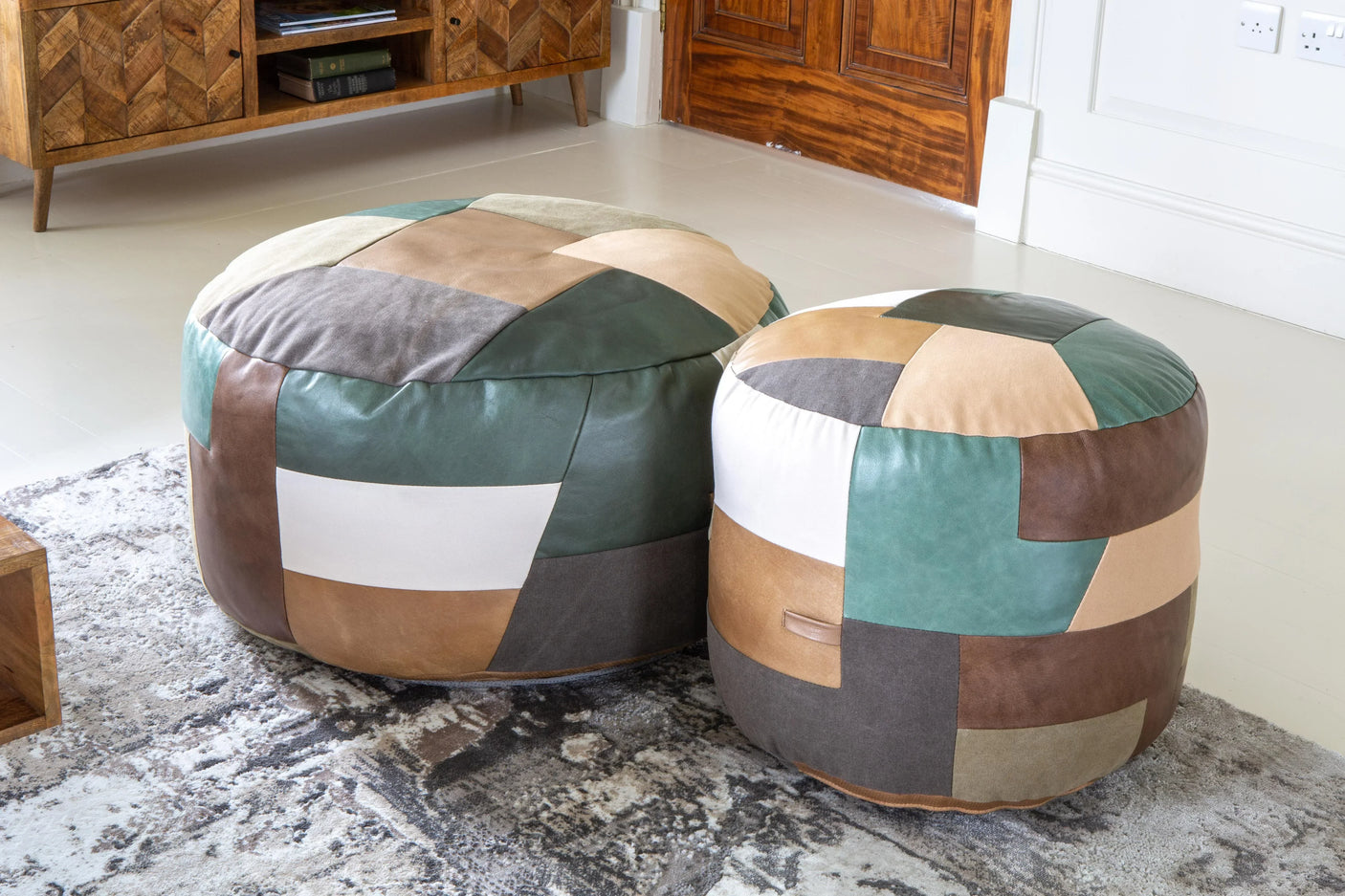 Pair of patchwork leather pouffes in earthy tones on patterned rug in living room