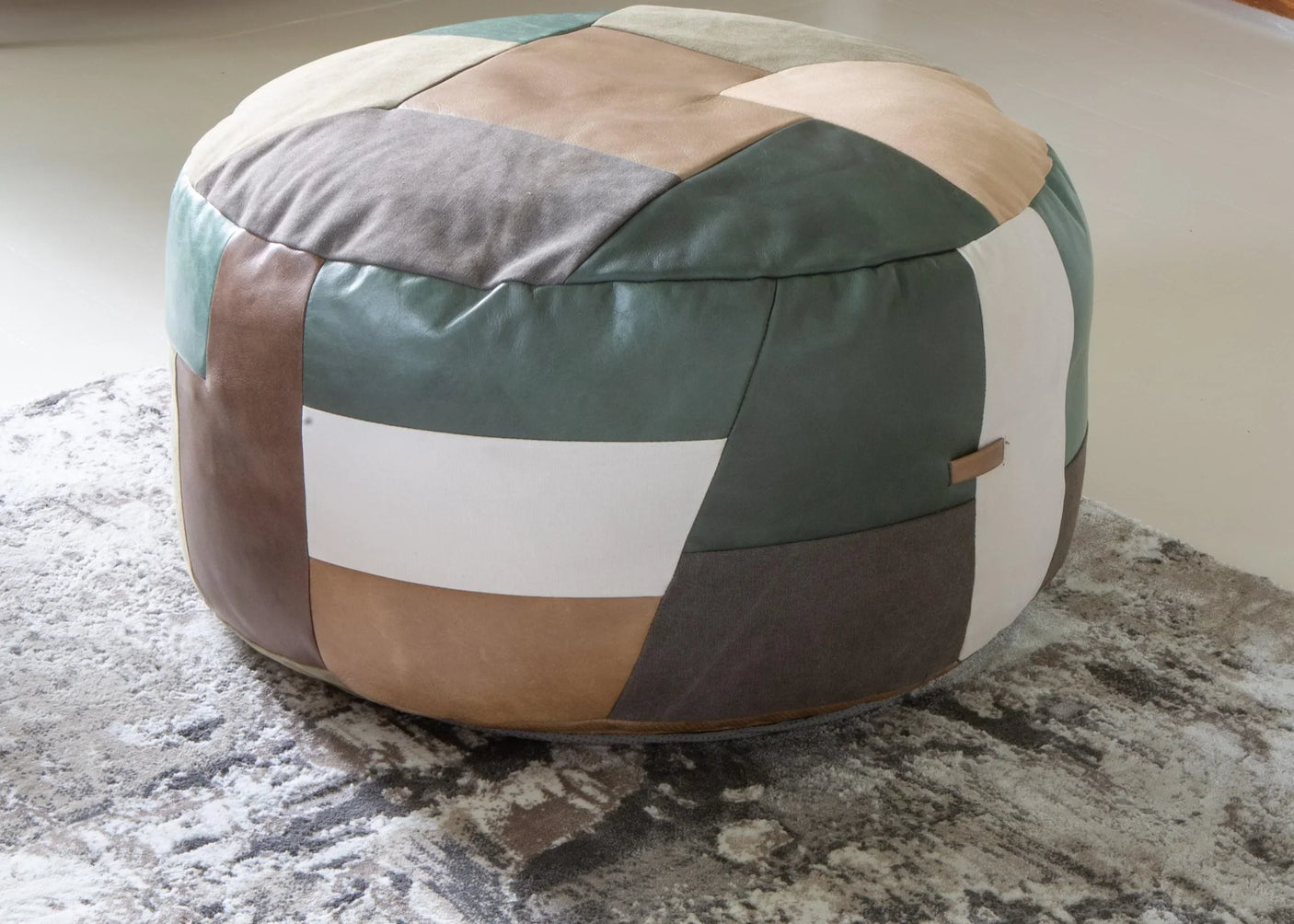 Patchwork leather pouffe ottoman in green, brown and cream on textured rug