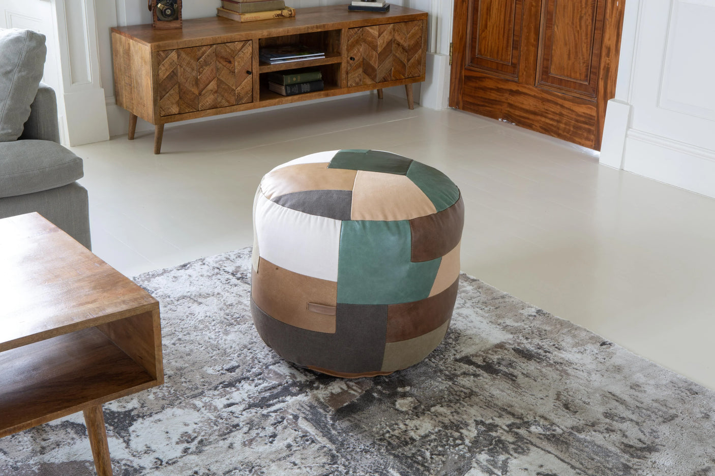 Patchwork leather pouffe in neutral and green tones on modern living room rug