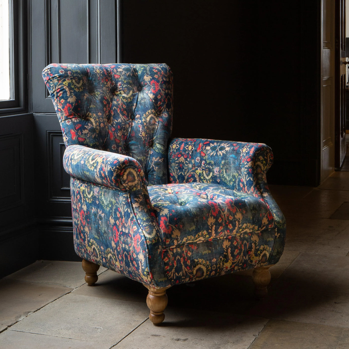 Patterned fabric armchair with wooden legs in a corner setting