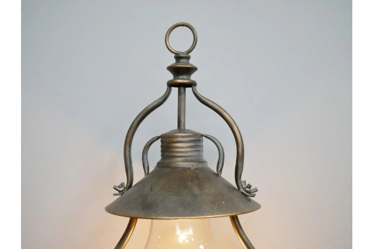 Metal pendant light with glass shade and vintage style fittings against a neutral wall