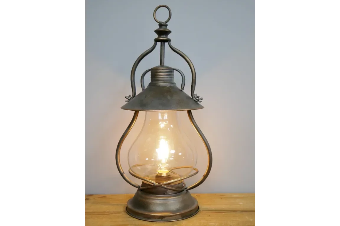 Vintage metal lantern table lamp with clear glass shade and warm glowing bulb