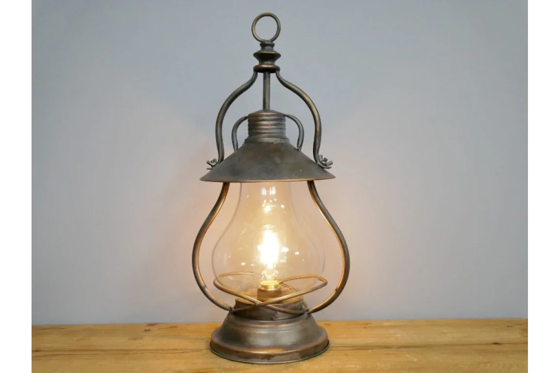 Vintage metal lantern table lamp with exposed filament bulb on wooden surface