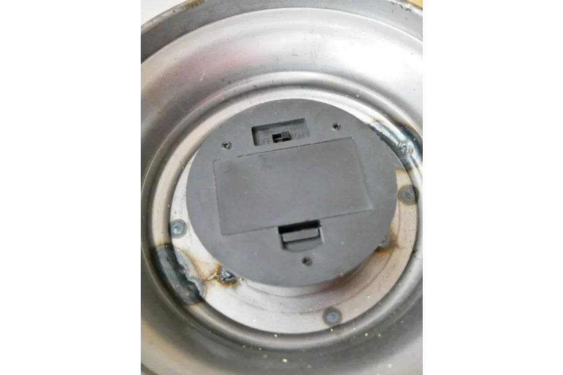 Closeup of black battery compartment with switch on round stainless steel base