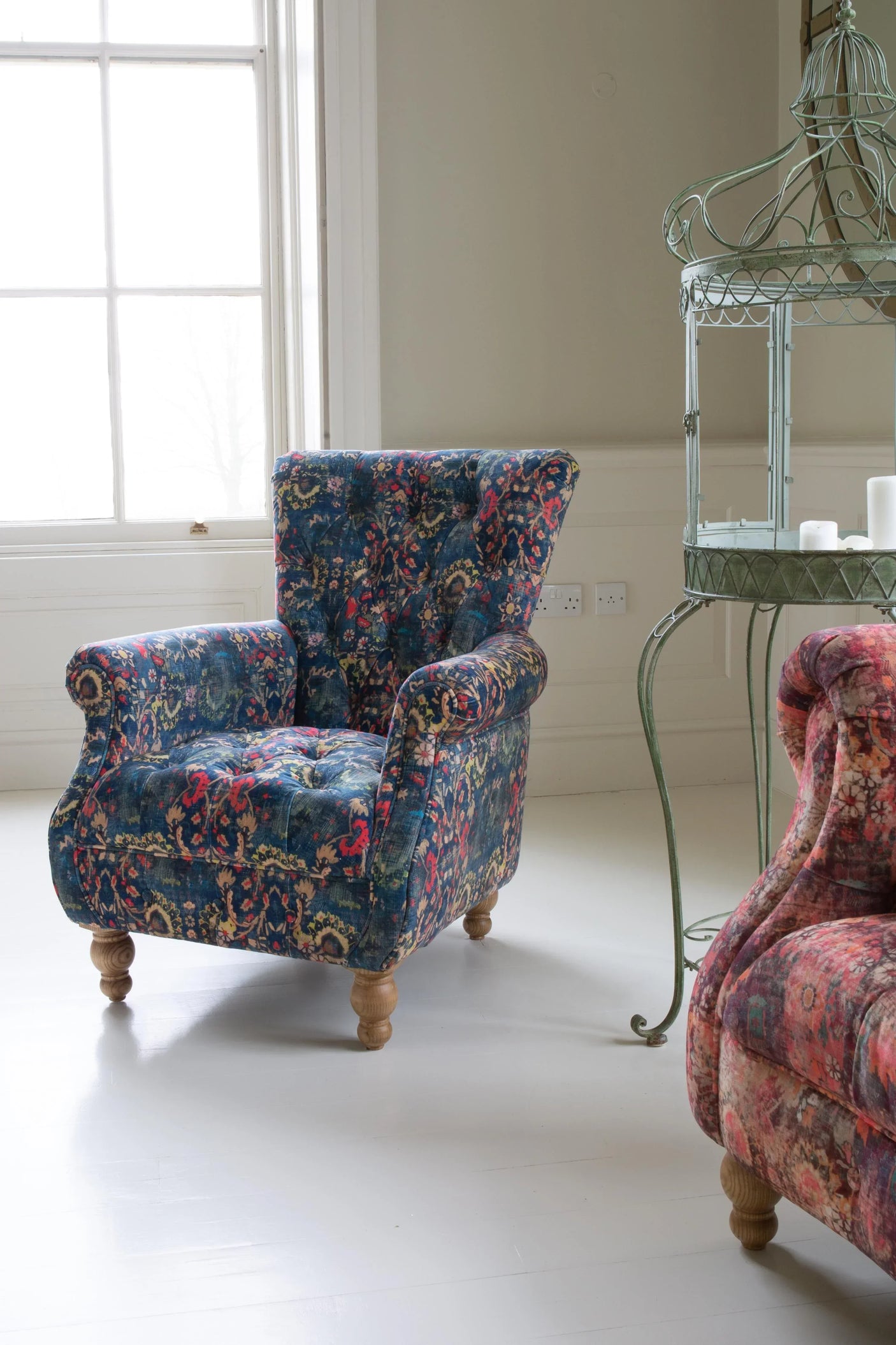 Blue floral armchair with wooden legs in bright living room near window