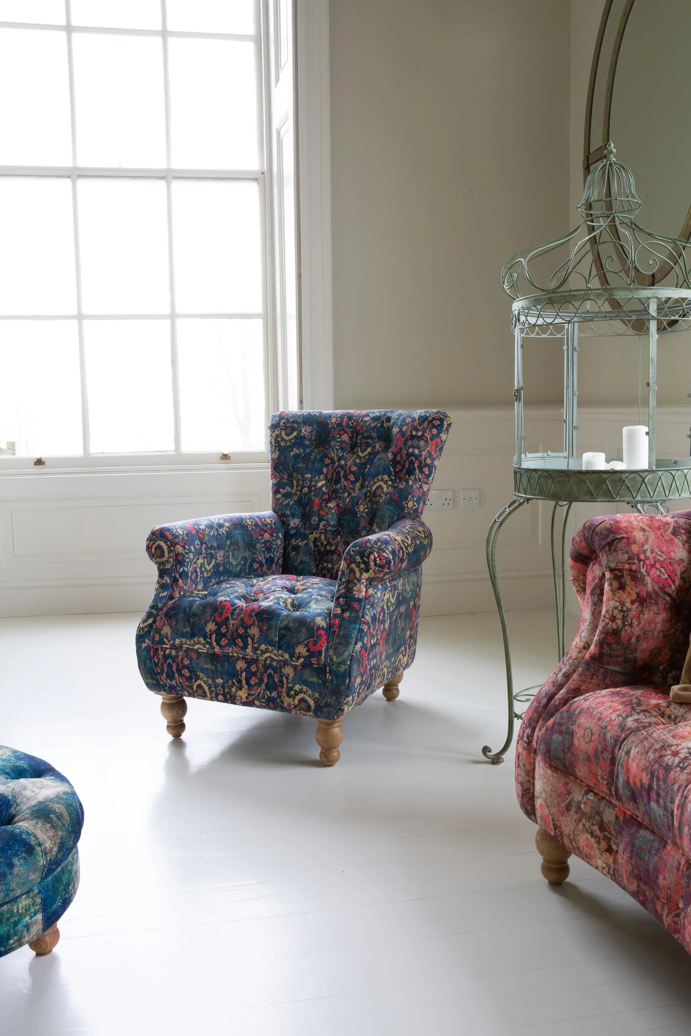 Blue patterned armchair with wooden legs in a bright living room with large window