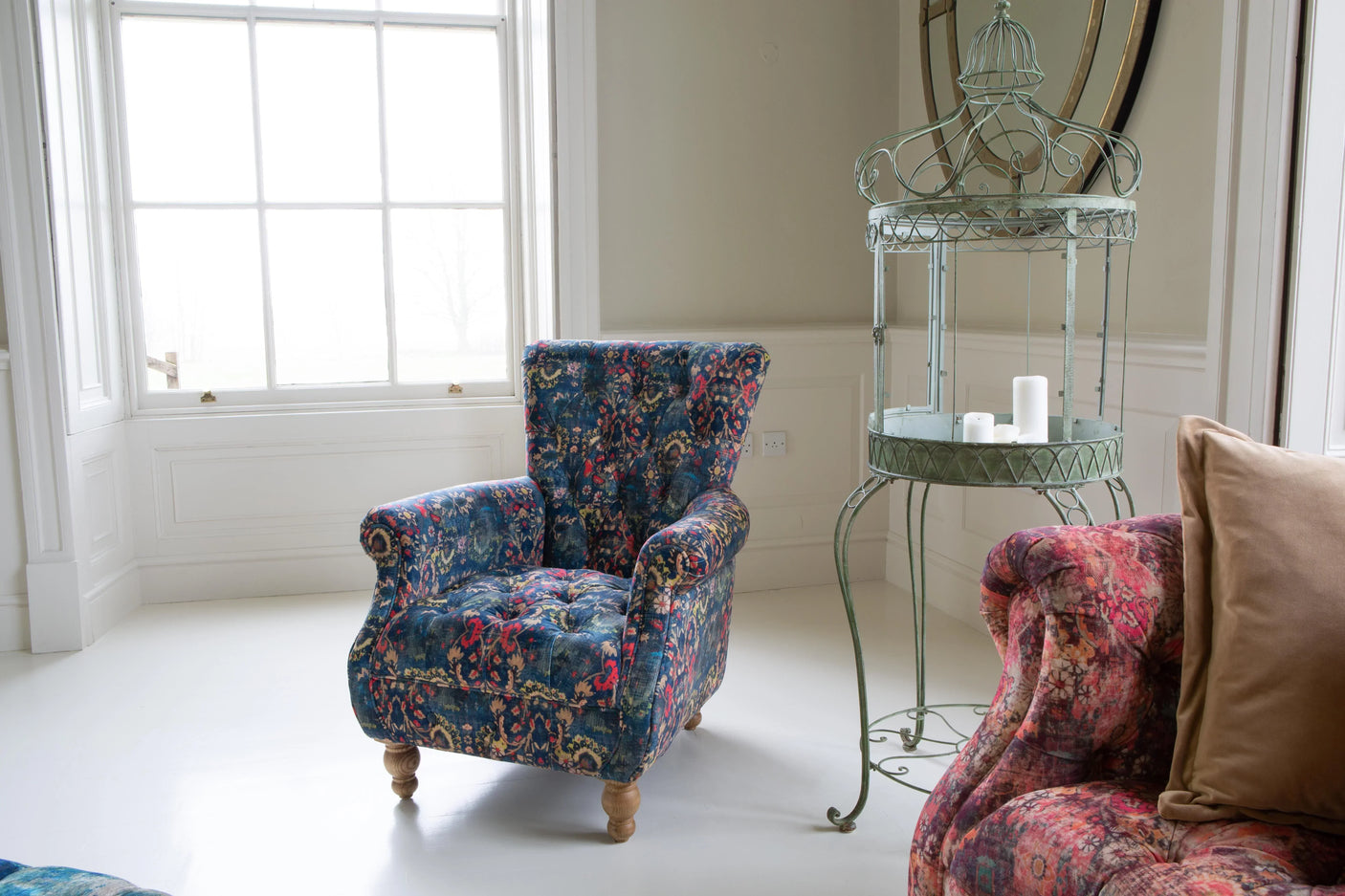 Patterned fabric armchair with wooden legs in bright living room near window and side table