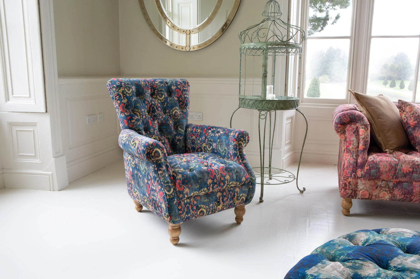 Blue floral fabric armchair with tufted design and wooden legs in a bright living room