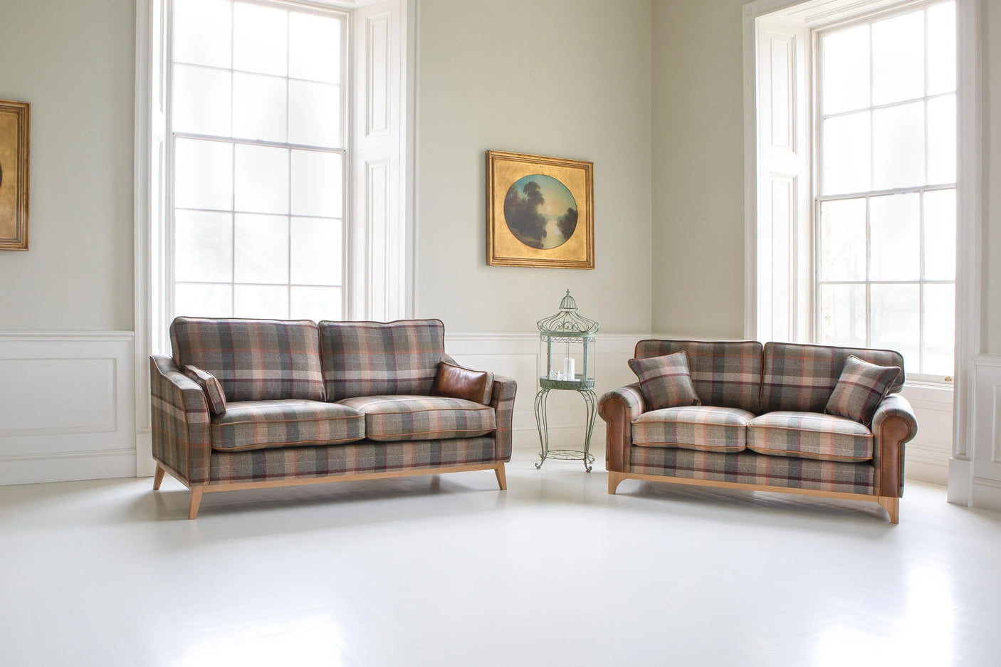 Plaid fabric sofas with wooden legs in bright living room with large windows and wall art
