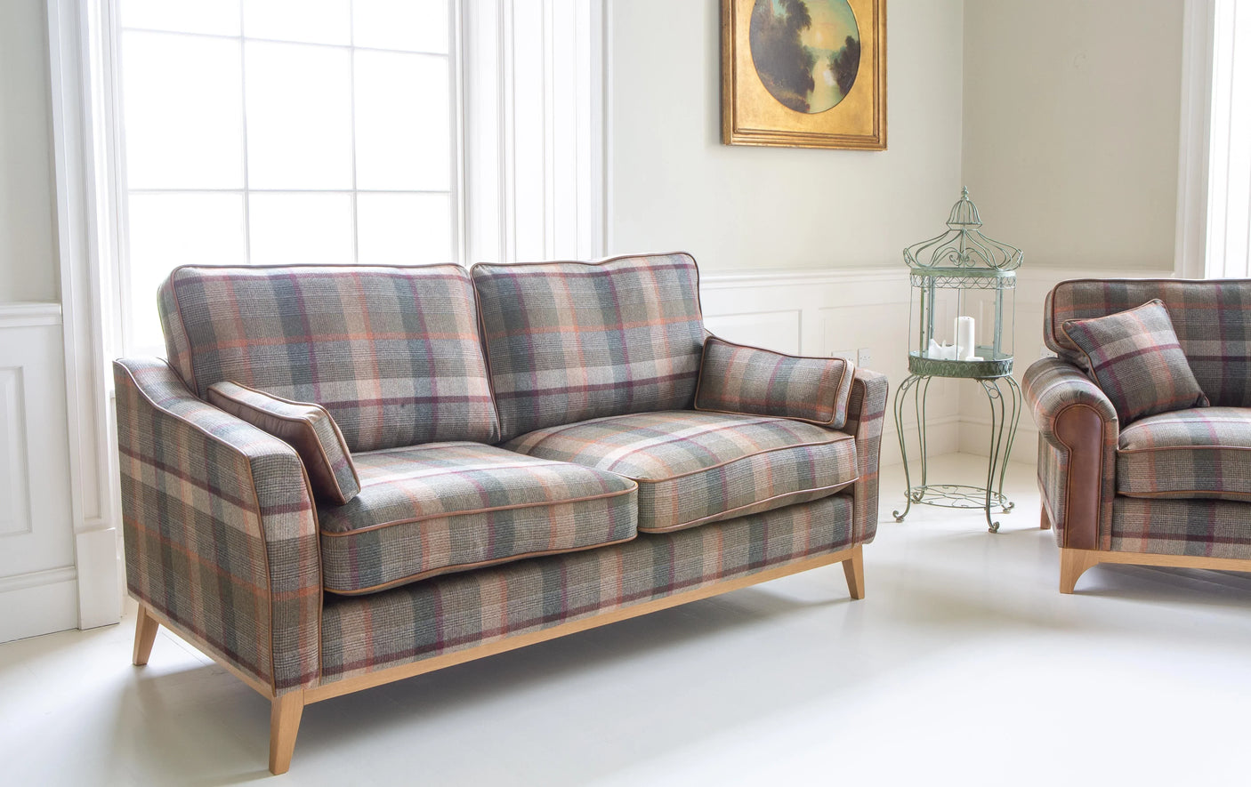 Tartan fabric sofa with wooden legs in a bright living room beside a large window