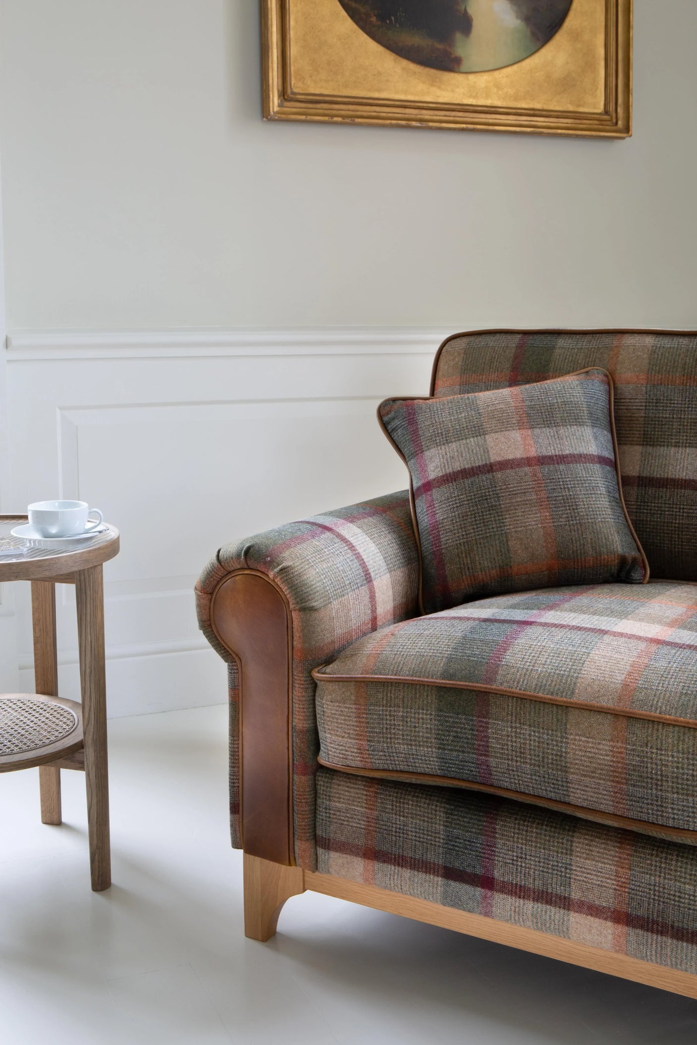 Plaid fabric sofa with matching cushion and wooden legs next to round side table
