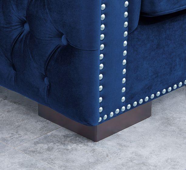 Blue velvet sofa corner with button tufting and silver stud detailing on wooden base