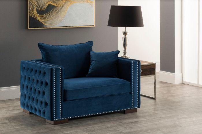 Blue velvet armchair with studded arms in modern living room next to side table and lamp