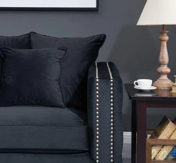 Dark fabric sofa with studded armrest beside wooden side table and lamp