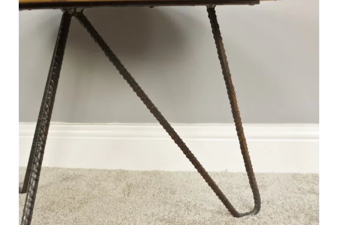 Closeup of industrial metal table leg with hairpin design on carpeted floor