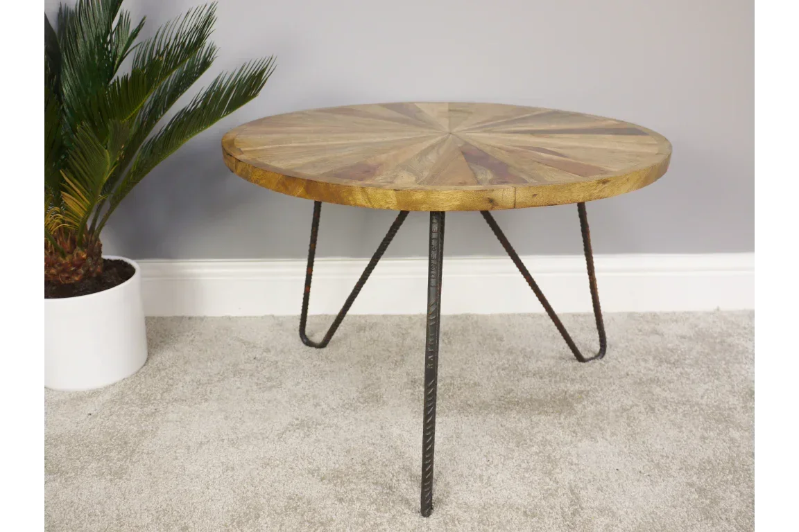 Round wood coffee table with metal hairpin legs on carpet next to potted plant