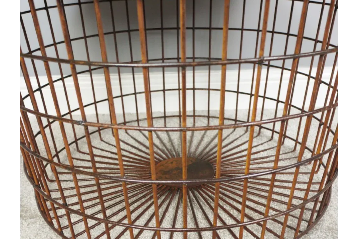 Round metal wire basket table base in rustic finish on carpeted floor