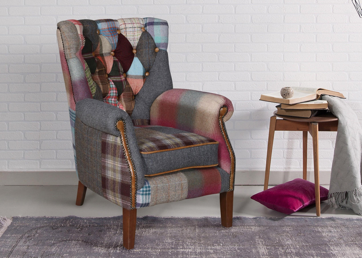 Patchwork upholstered armchair with wooden legs beside a side table and velvet cushion