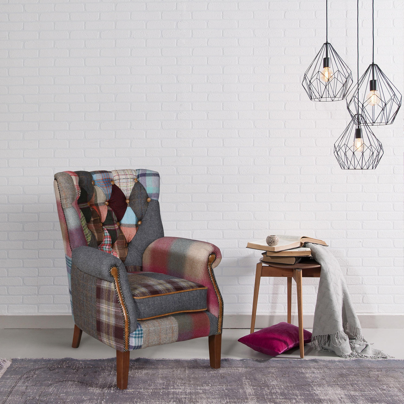 Patchwork armchair with wooden legs beside wooden side table, pendant lights overhead