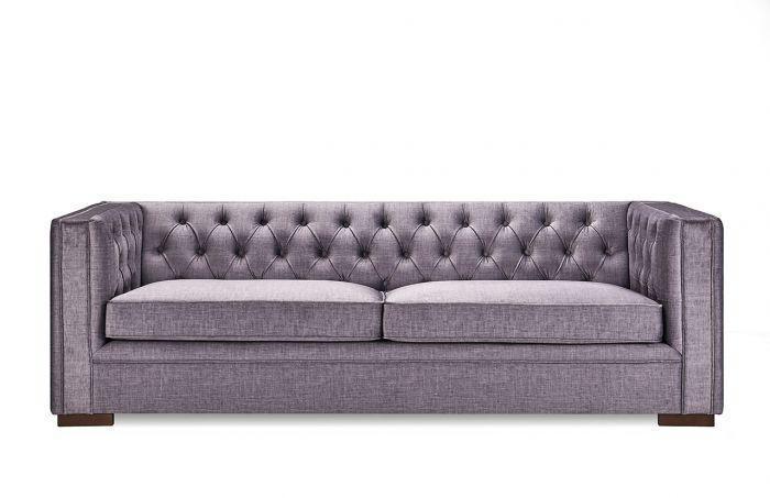Grey fabric sofa with deep button tufting and square arms on wooden legs