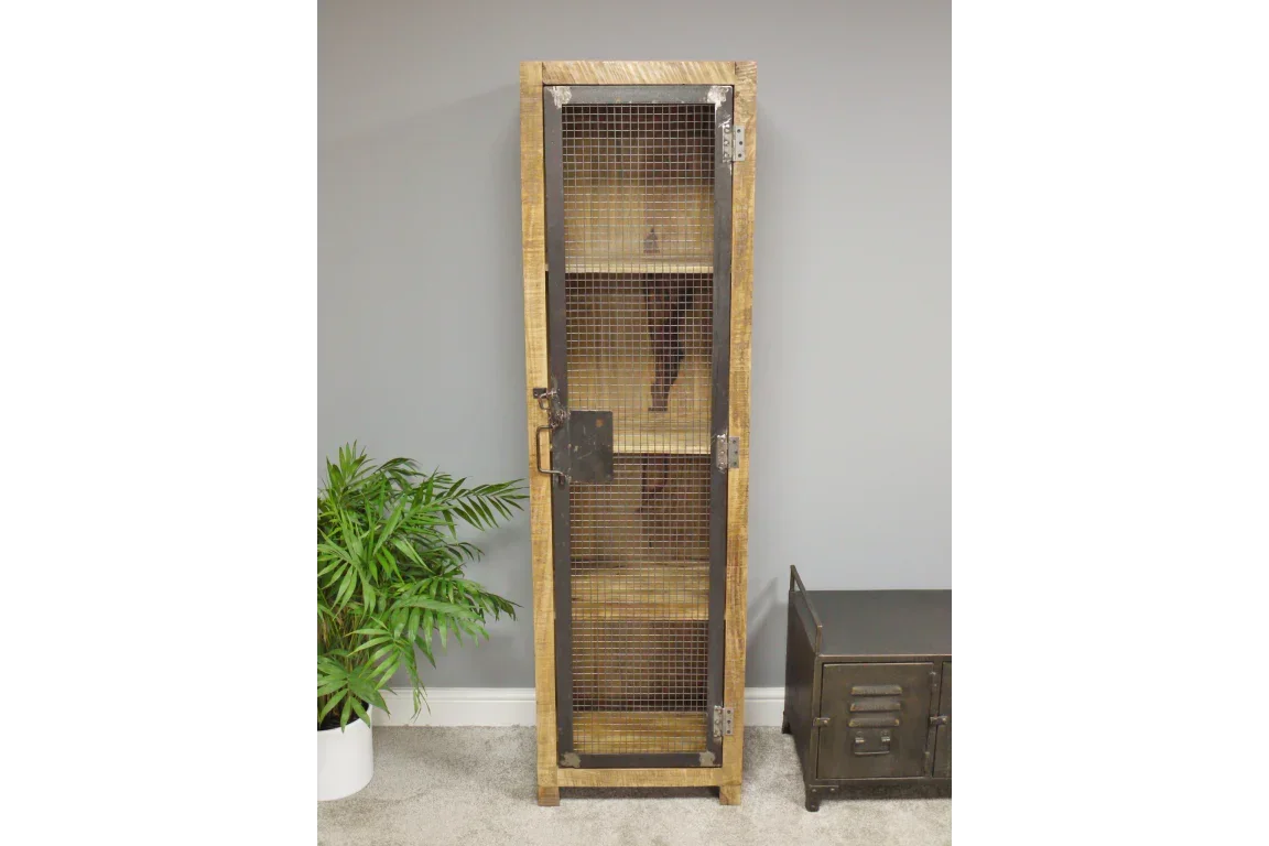 Tall industrial wooden cabinet with mesh metal door and shelves against grey wall