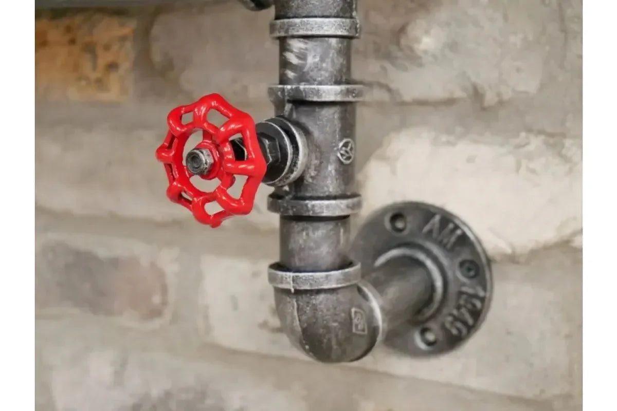 Industrial metal pipe wall light fitting with red valve handle on brick backdrop