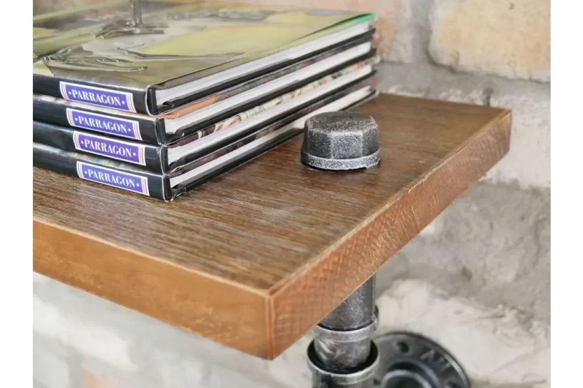 Industrial wood wall shelf with metal pipe bracket, books stacked on corner against brick wall