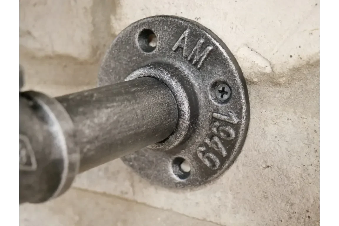 Industrial steel pipe bracket mounted on wall with visible screw fittings
