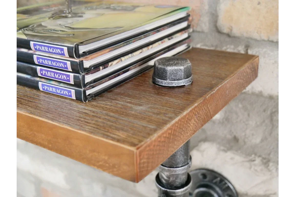 Industrial wall shelf with dark wood surface and metal pipe brackets against brick wall