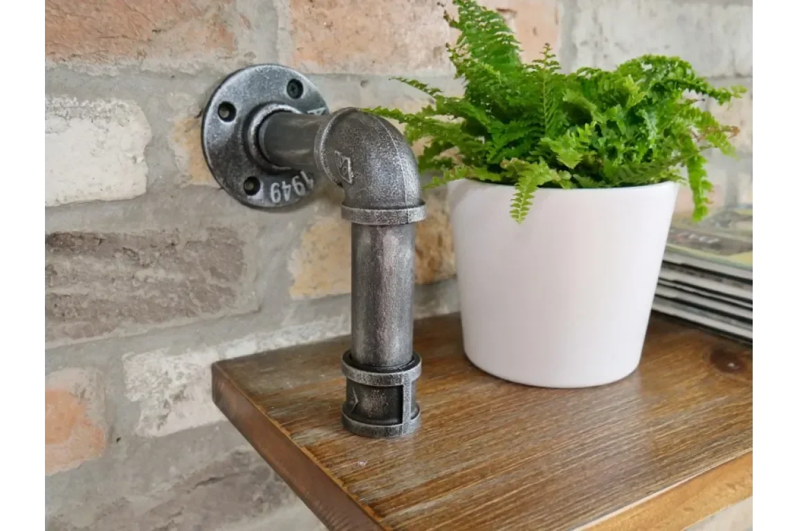 Industrial pipe shelf bracket mounted on brick wall with white plant pot on wooden shelf