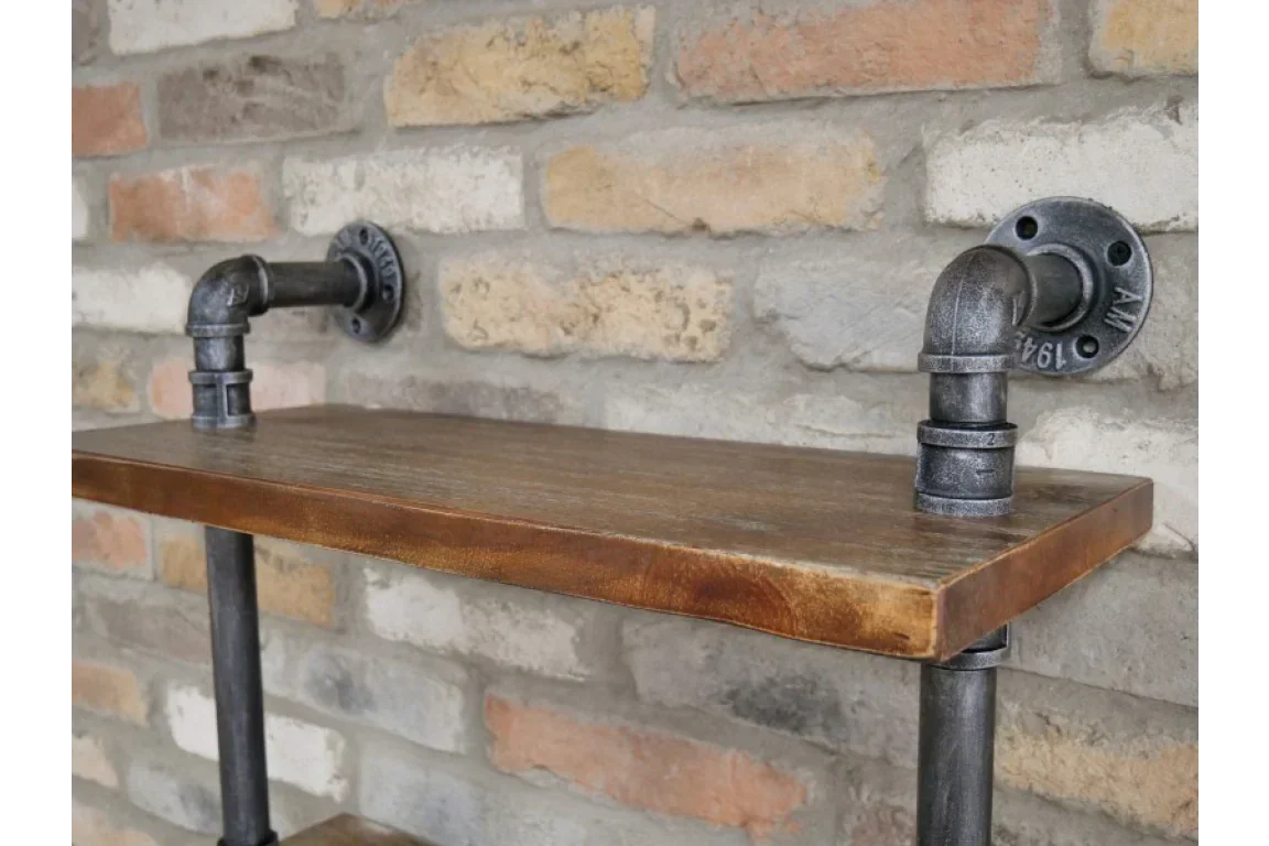 Industrial wall shelf with metal pipe brackets and wooden plank against brick wall