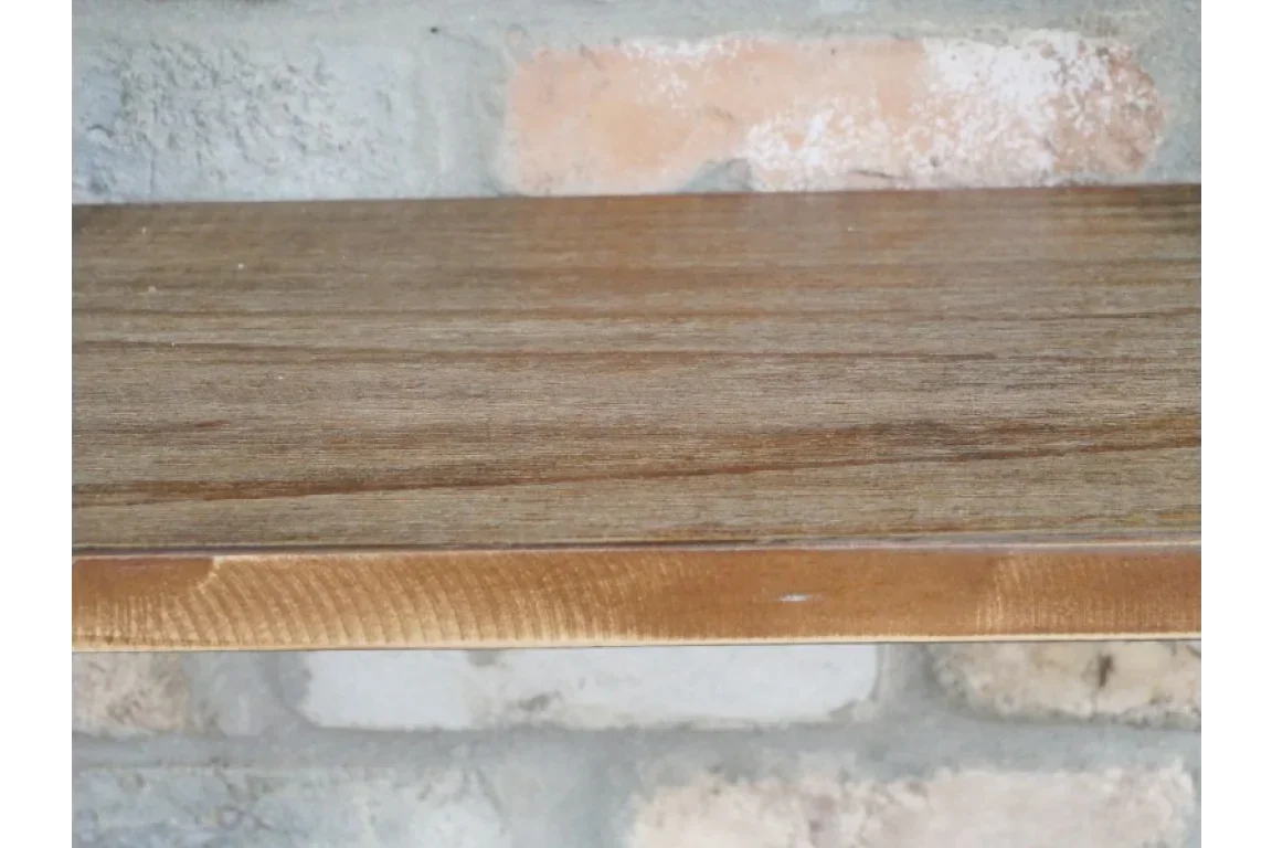 Wooden wall shelf with natural grain mounted on a light brick background