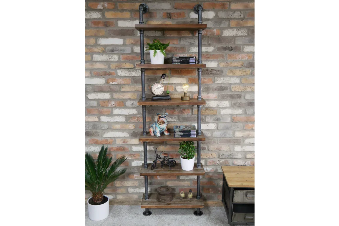 Industrial pipe shelving unit with wooden shelves against brick wall, decorated with plants and books