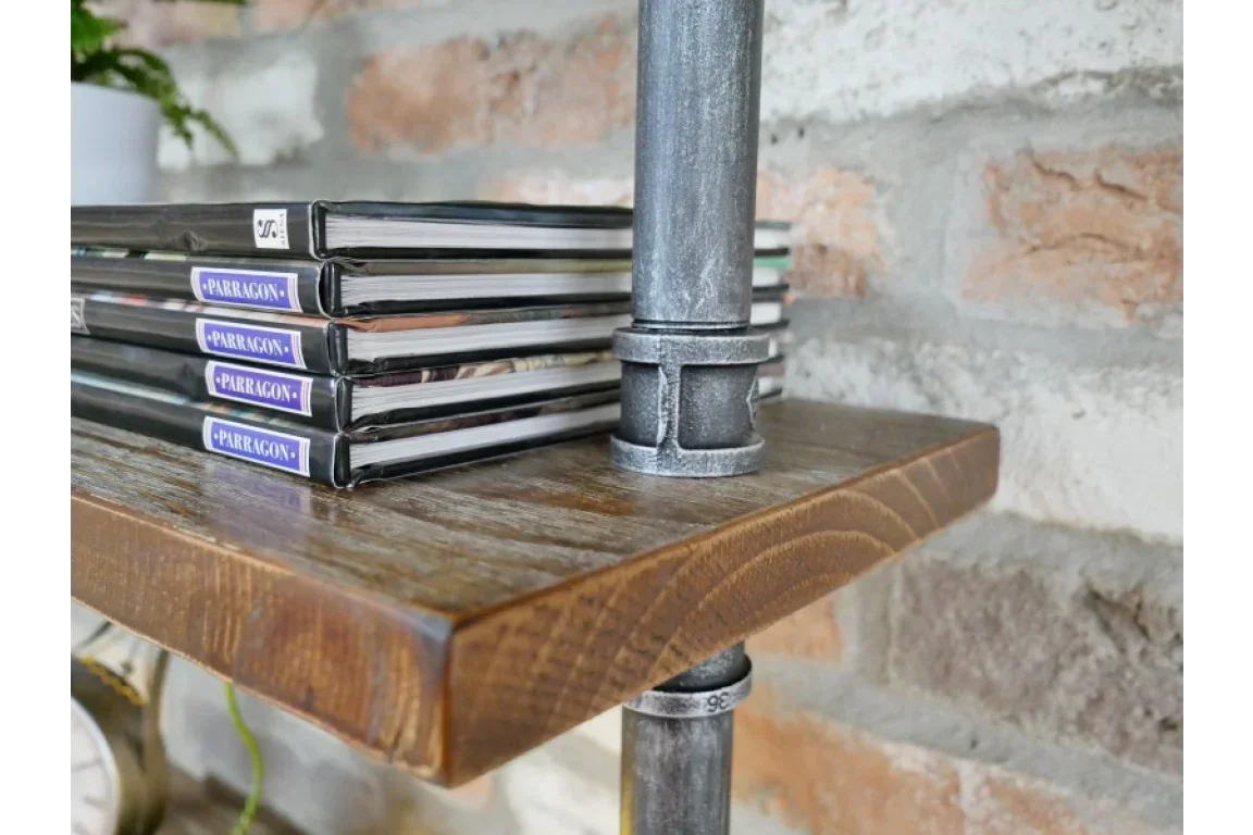 Industrial pipe and wood shelf with stacked books against exposed brick wall
