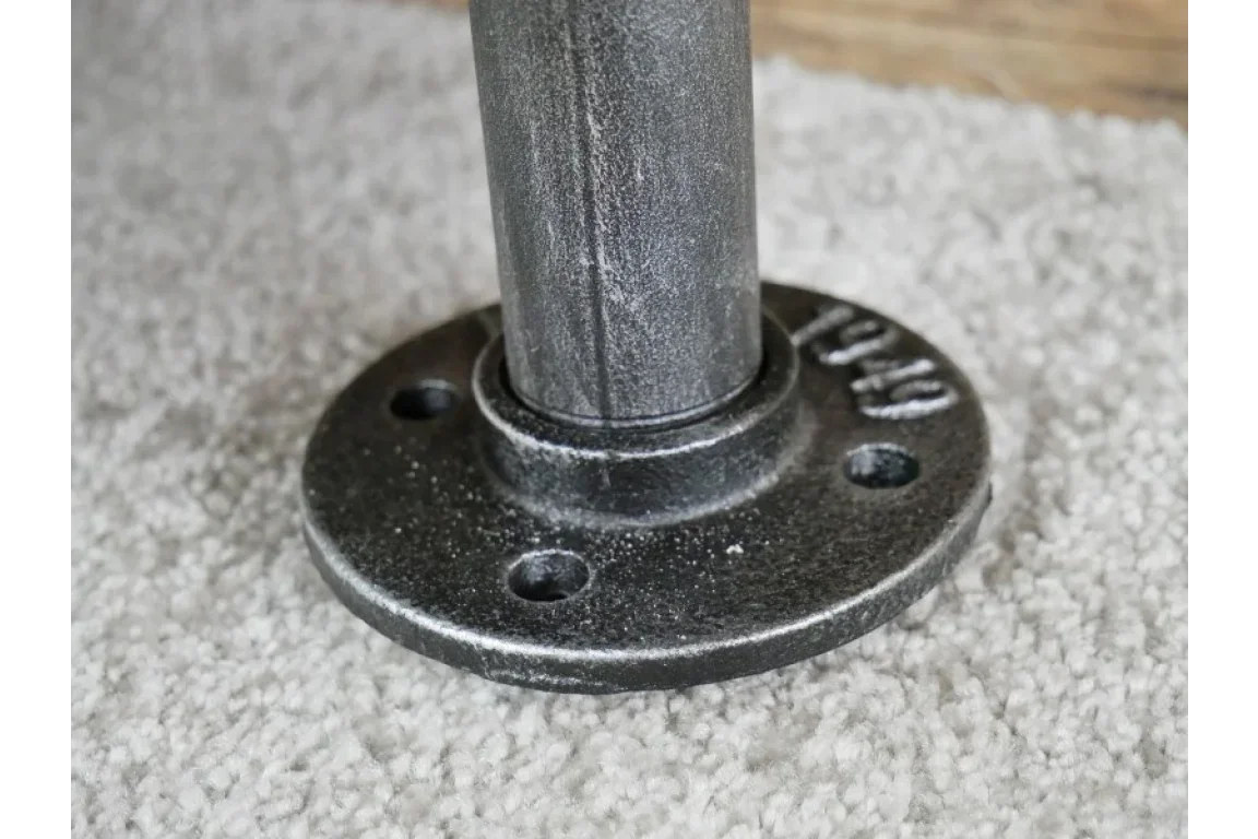 Black metal table leg with round base resting on light textured carpet