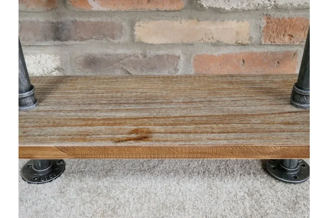 Wooden industrial pipe shelf with metal supports against exposed brick wall