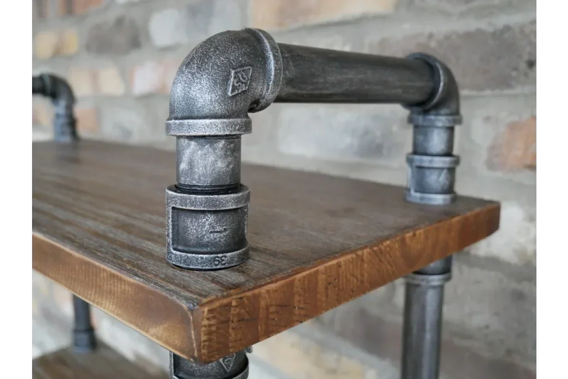 Industrial pipe shelf with metal fittings and wooden surface against brick wall