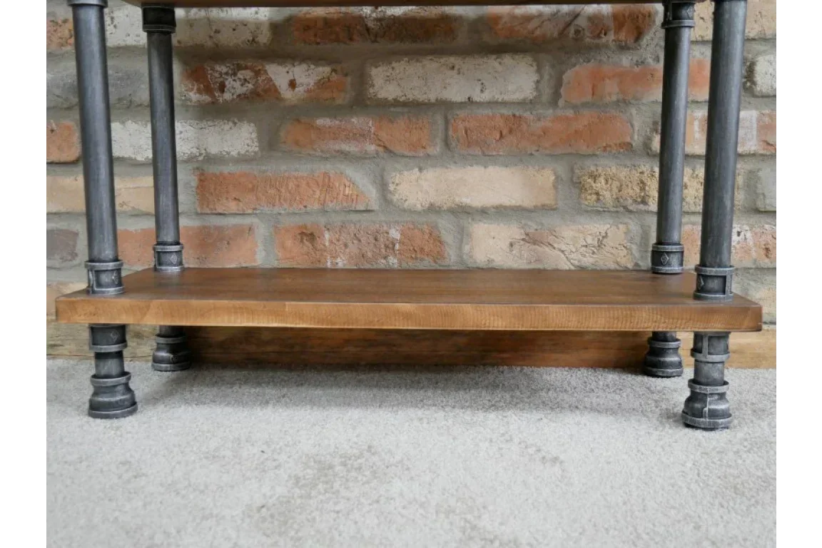 Industrial style wooden shelf with black metal pipe legs against brick wall