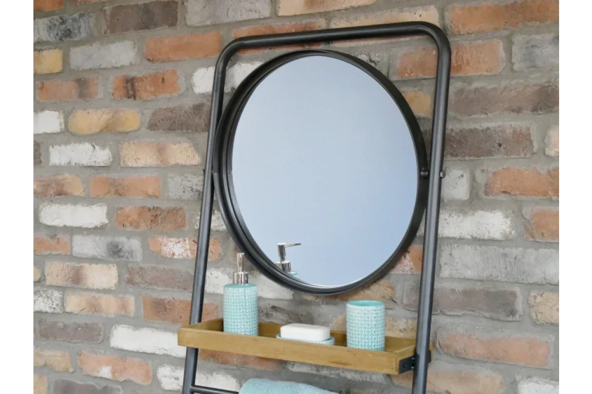 Round wall mirror with black metal frame, shelf, and blue bathroom accessories on brick wall