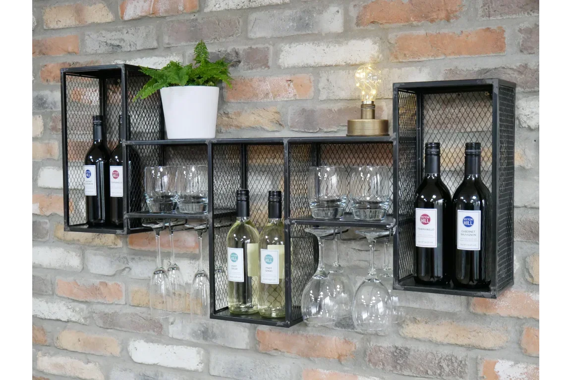 Black metal wall wine rack with bottles, glasses, plant and lamp on exposed brick wall