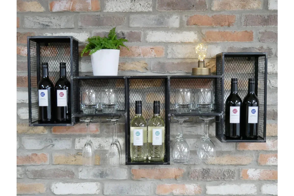 Industrial wall wine rack with mesh shelves, wine bottles, glasses, and decor on brick wall