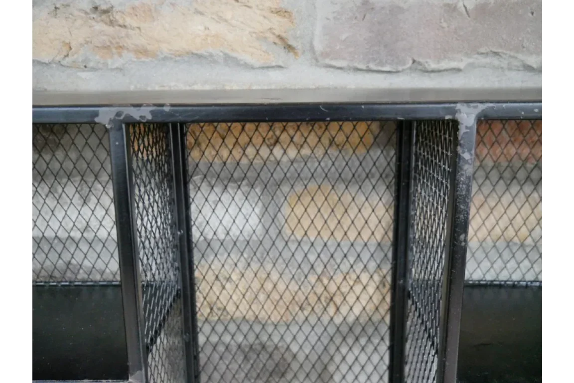 Black metal mesh fireplace screen in front of stone wall