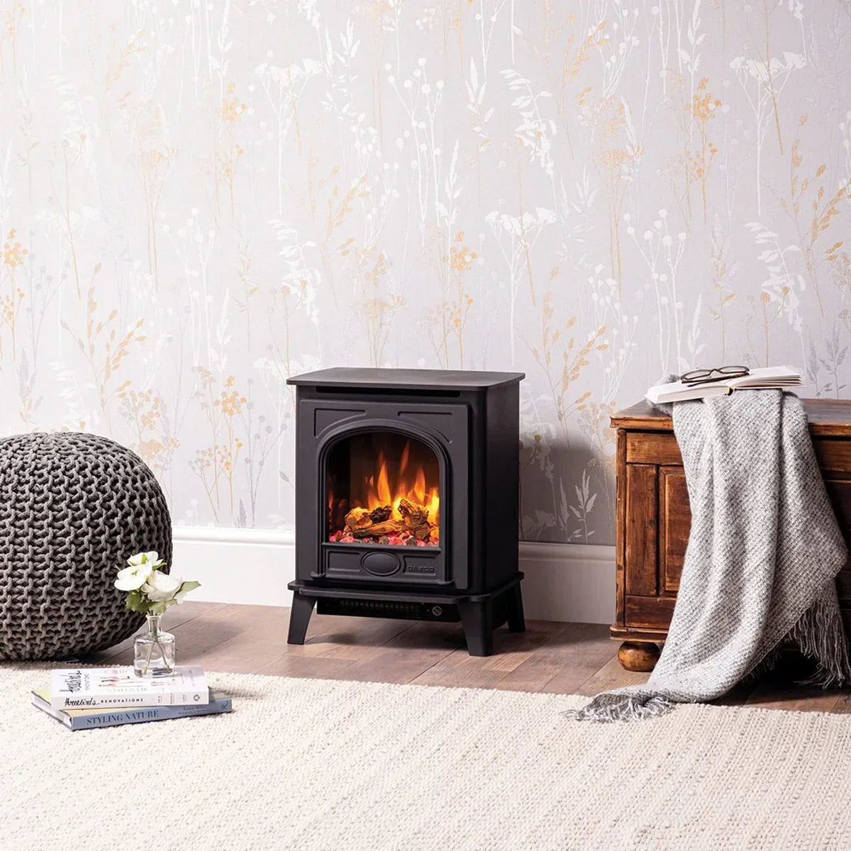 Black electric stove heater in modern living room with grey pouf and wooden chest